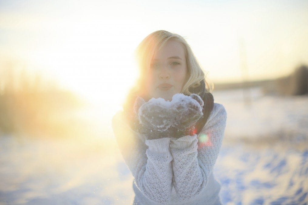 Woman blowing snow from hands