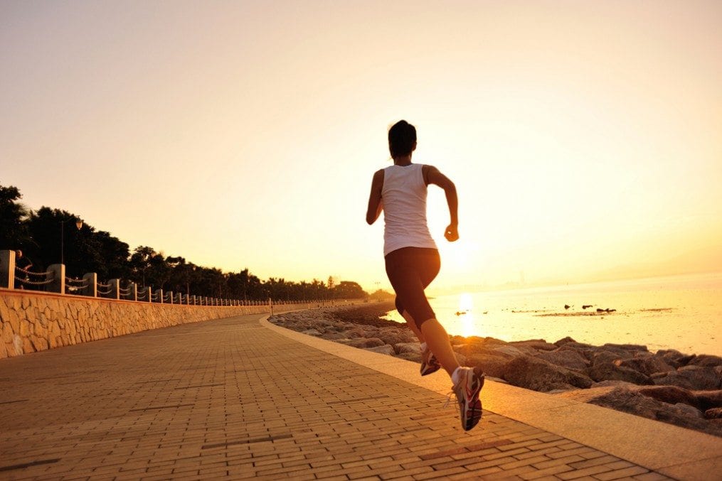 Woman running towards sunset
